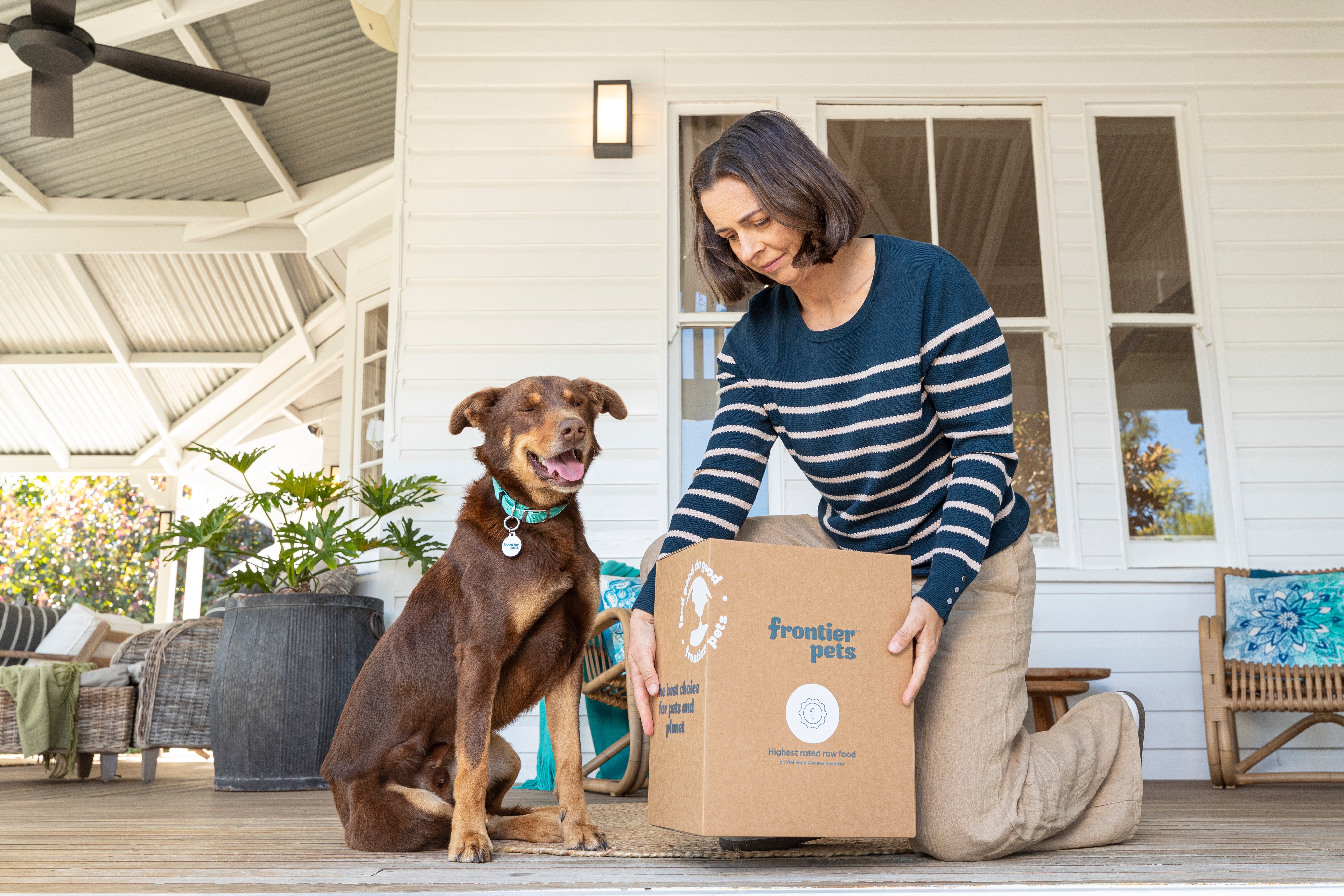 Women picking up dog food delivery with brown dog